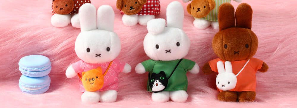 Set of plush toy bunnies with various outfits on a pink background